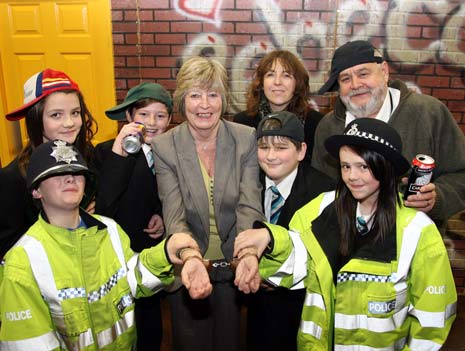 CRIME DOESN’T PAY: Councillor Carol Hart (centre) is handcuffed by two ‘police officers’ in a ‘Prison Me No Way!’ street crime scanario at Shirebrook Academy with students (from left) Connor Slaney, Courtney Parsons, John Allen, Owen Morgan and  Megan Jennyford, academy principal Julie Bloor and retired police officer Ollie Woods